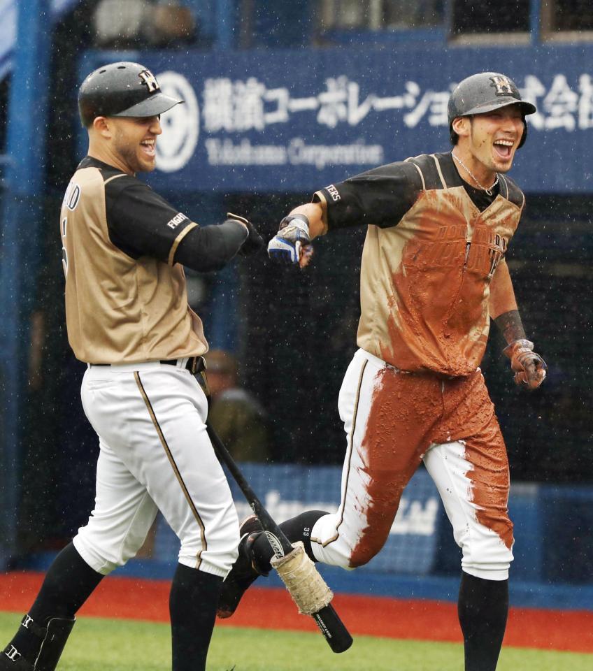 　１回、中田の犠飛で生還し、泥だらけのユニホームでレアード（左）とタッチする大田