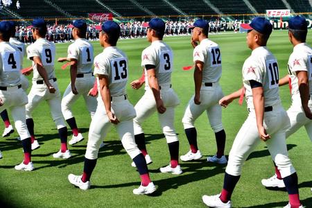 飲料のペットボトルをお尻のポケットに入れ入場行進する八戸学院光星の選手たち＝甲子園（撮影・佐藤厚）