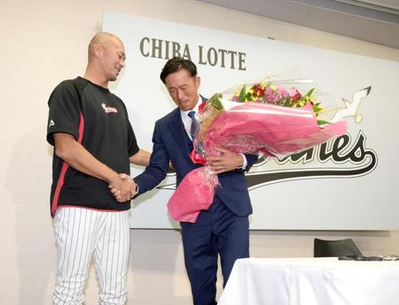 　引退会見の後、福浦（左）から花束を贈られ涙ぐむ岡田