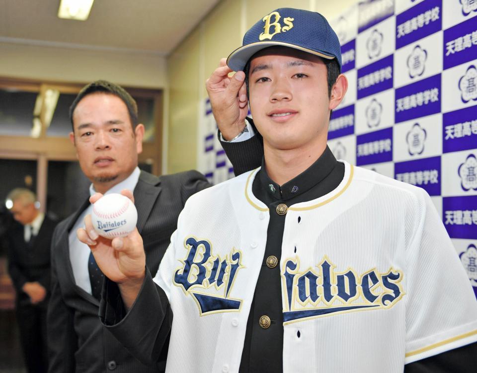 天理・太田椋（右）はオリックス１位指名され、オリックスの打撃投手を務める父の暁さんとカメラに納まる（撮影・山口登）