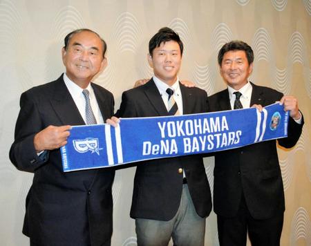 　吉田スカウト部長（左）、武居スカウトとともにタオルを掲げて笑顔を見せる上茶谷（中央）