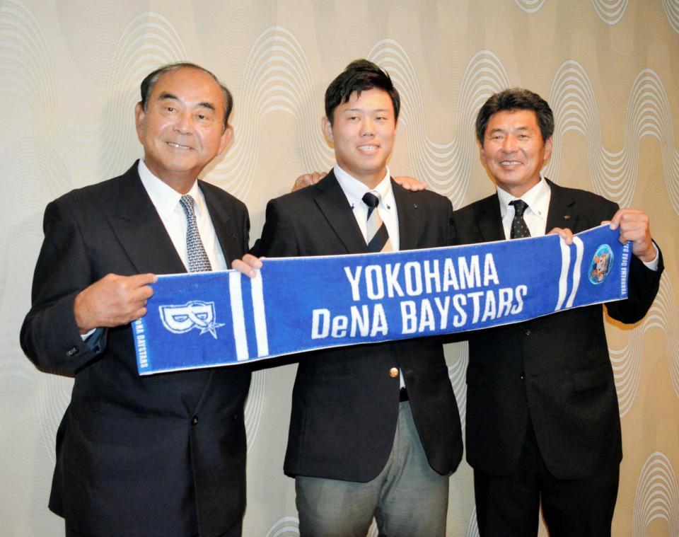 　吉田スカウト部長（左）、武居スカウトとともにタオルを掲げて笑顔を見せる上茶谷（中央）