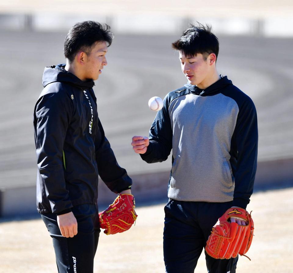 ボールを触りながら日本ハム・柿木蓮と談笑する日本ハム・吉田輝星（右）＝鎌ケ谷（撮影・出月俊成）