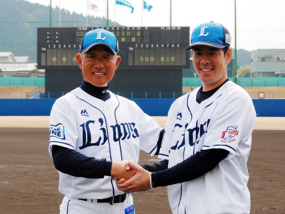 　開幕投手を伝えるスコアボードをバックに握手を交わす辻監督（左）と多和田