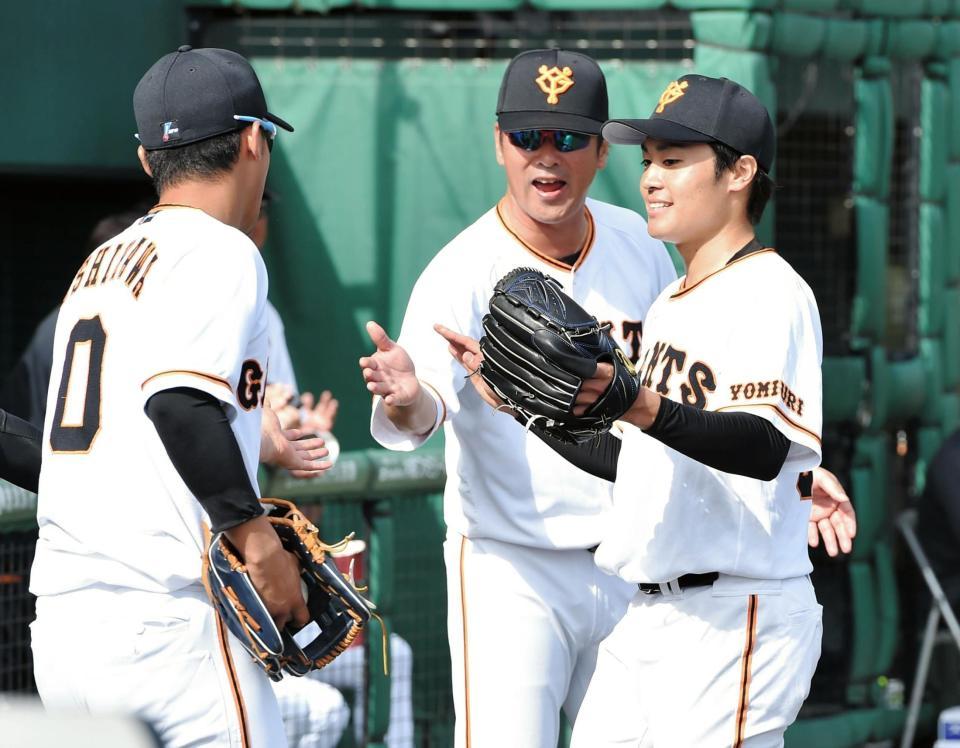 　８回、降板後に吉川尚輝（左）らに迎えられ、笑顔を浮かべる巨人・坂本工宜（右）