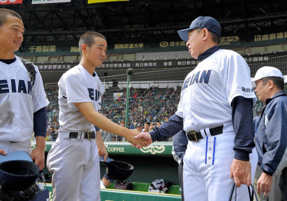 　甲子園通算３０勝を挙げ、完投した野沢（左）と握手する龍谷大平安・原田監督