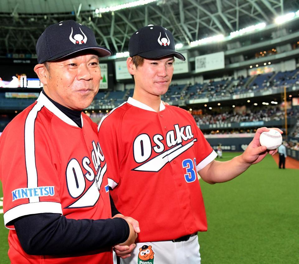 プロ初勝利を挙げウイニングボールを手に西村監督（左）と握手を交わすＫ－鈴木