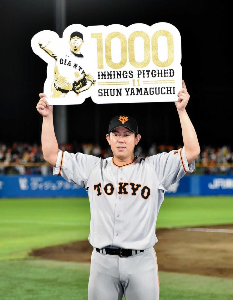　１０００投球回数を達成し、ボードを掲げる山口（撮影・西岡正）