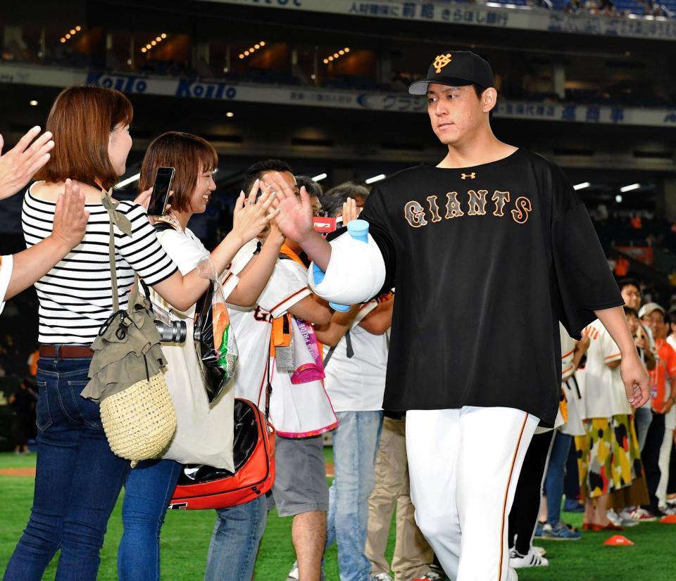 　今季５勝目を挙げ、ファンとタッチを交わす巨人・桜井俊貴（右）＝東京ドーム