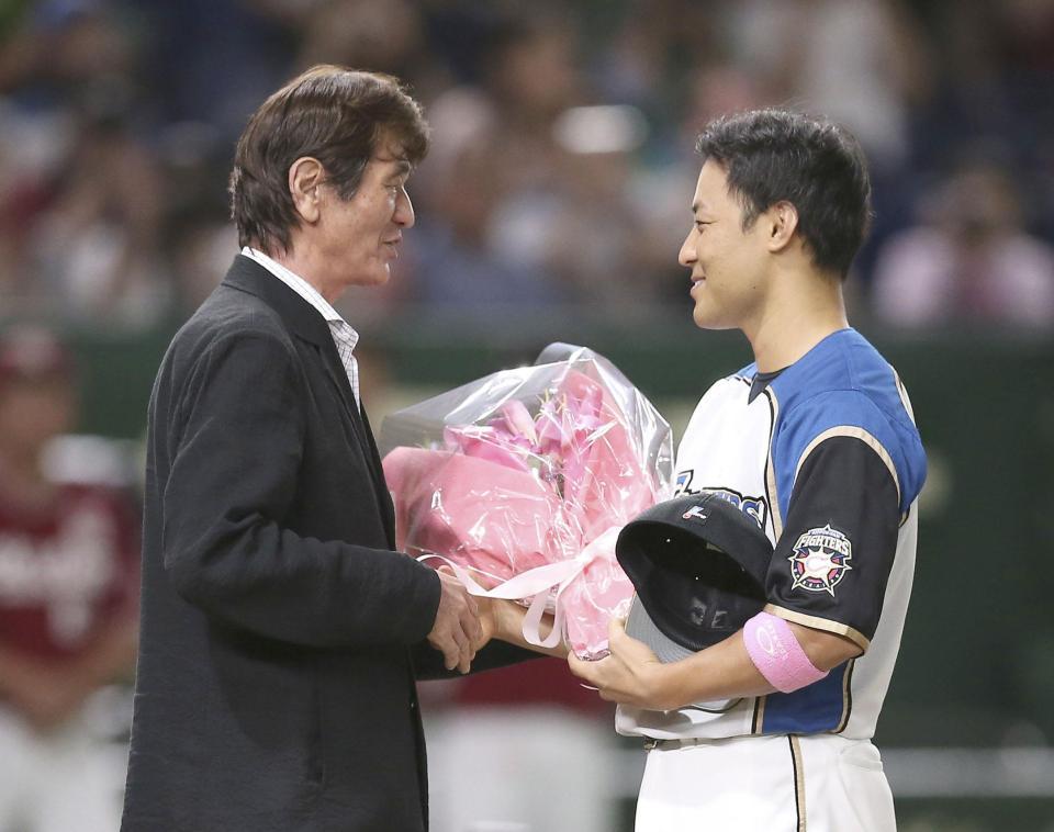 　試合前、入団当時の監督だった大島康徳氏（左）から花束を受け取る、今季限りで引退する日本ハム・田中賢