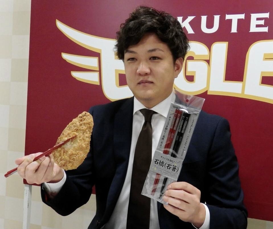 　チャンスをつかむ新グッズ「石箸」でカツをつかみアピールする楽天・石橋＝仙台市内の球団事務所