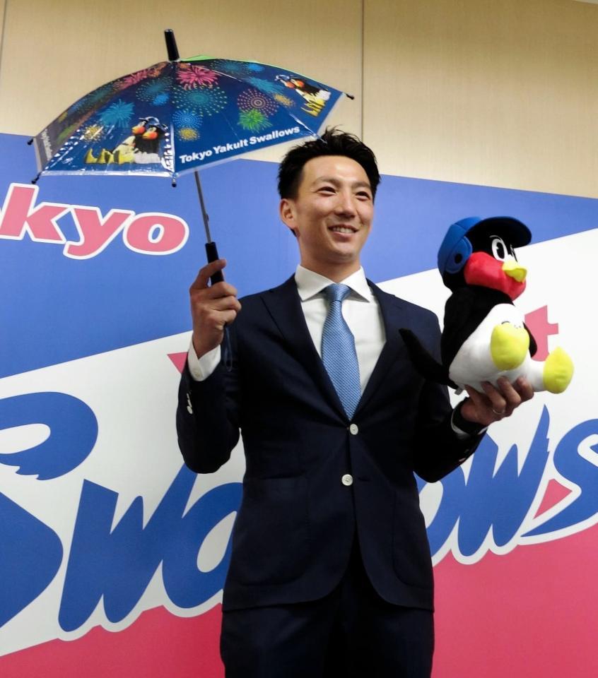 　ヤクルトと正式契約を結び、グッズを手に笑顔でポーズをとる嶋