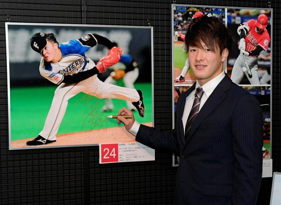 自身の写真にサインを入れる日本ハム・吉田輝星＝野球殿堂博物館（撮影・三好信也）