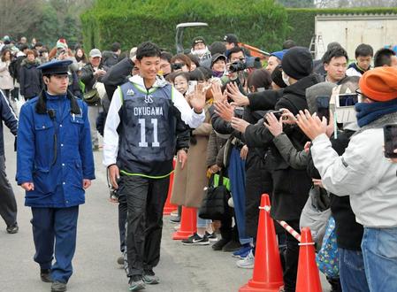 　新人合同自主トレを終えてファンとタッチを交わす奥川（撮影・堀内翔）