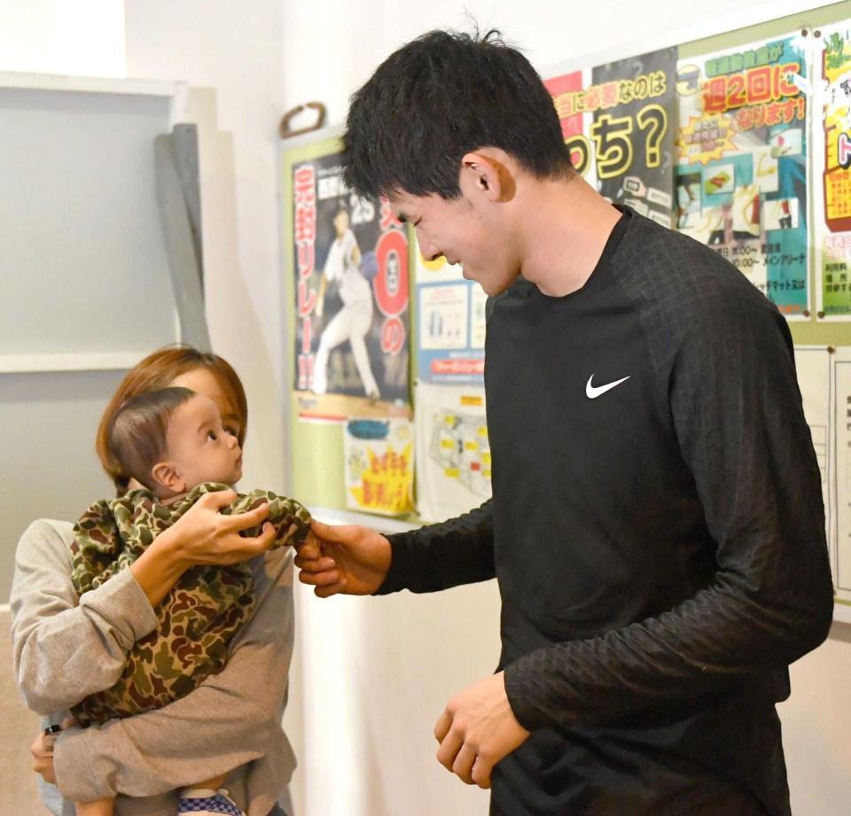 　赤ちゃんと握手する佐々木朗