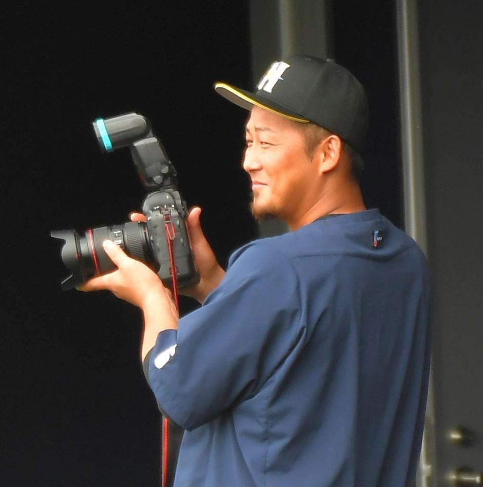 　カメラを手に笑顔を見せる中田