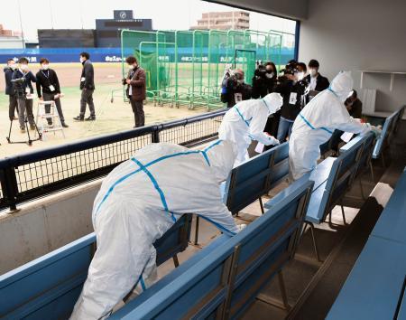 　中日の２軍本拠地ナゴヤ球場で一塁側ベンチ内を消毒する防護服の作業員＝３０日午前、名古屋市