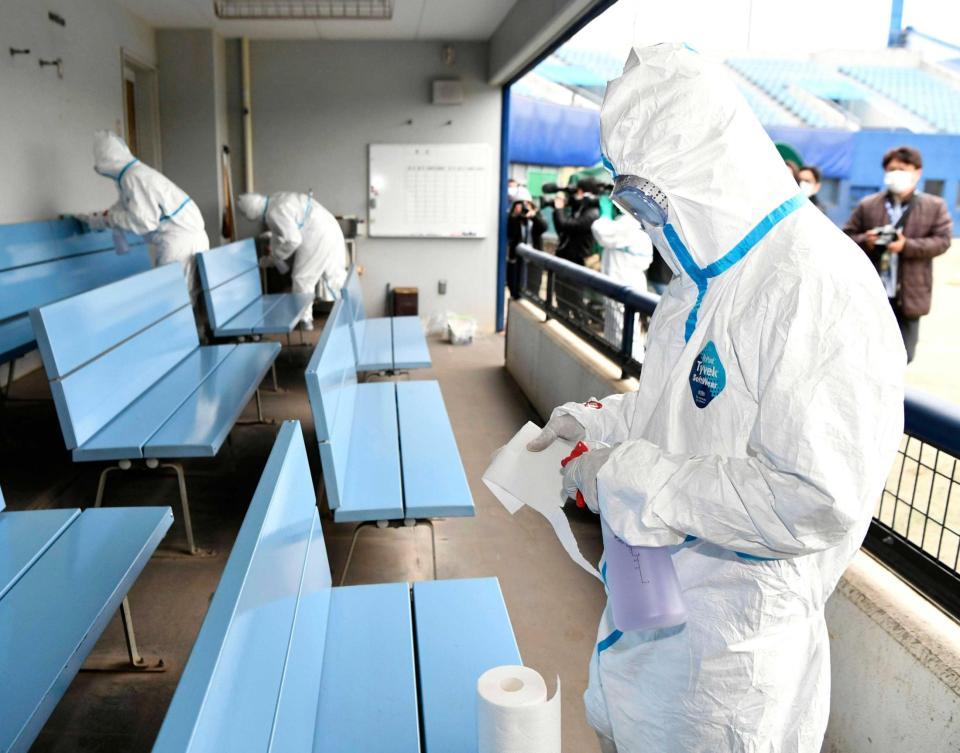 　ナゴヤ球場の一塁側ベンチ内を消毒する防護服の作業員