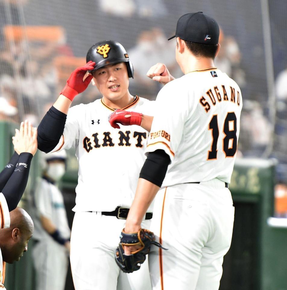 ４回、先制ソロを放ち、菅野（右）に祝福される巨人・岡本＝東京ドーム（撮影・西岡正）