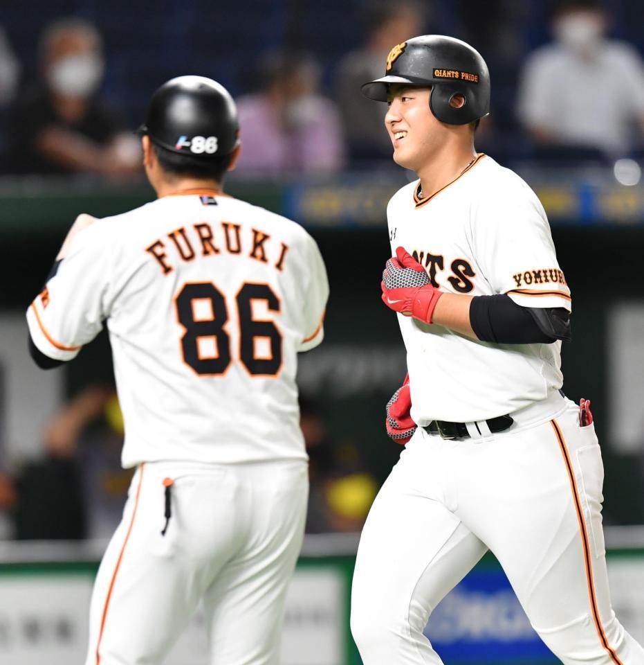 ４回、先制ソロを放ち、笑顔で生還する巨人・岡本（右）＝東京ドーム（撮影・西岡正）