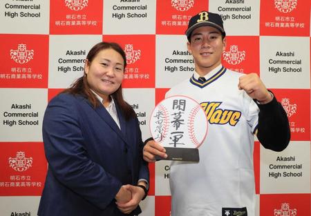 　ブルーウェーブ時代のユニホームでポーズを決める明石商・来田。左は乾スカウト