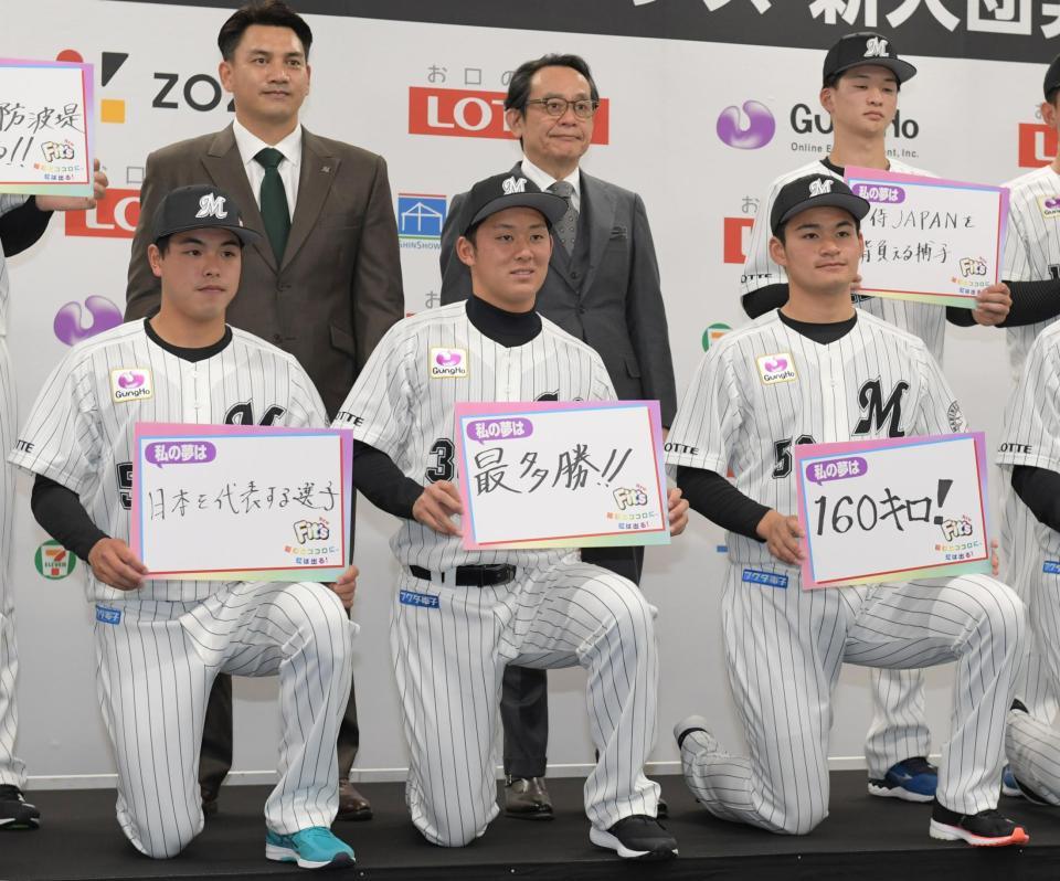井口資仁監督（上段左）の前で目標をボードに掲げる（左から）３巡目・小川龍成、１巡目・鈴木昭汰、２巡目・中森俊介＝埼玉県・ロッテイノベーションセンター（撮影・三好信也）