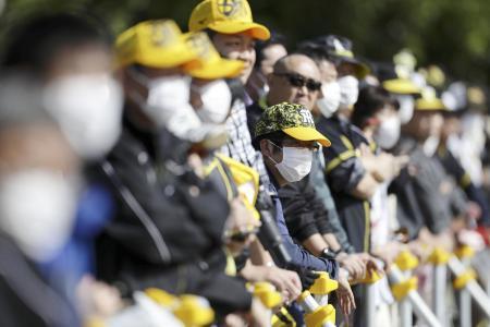 　２月、プロ野球・阪神のキャンプで、マスクを着け選手の練習を見つめるファン＝沖縄県宜野座村