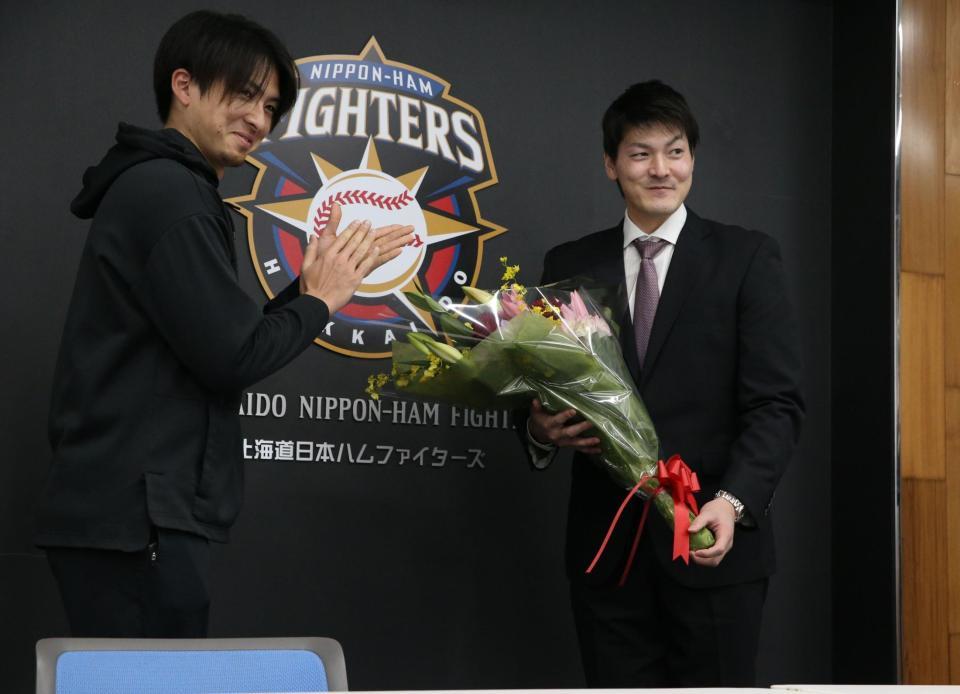 退団会見で上沢（左）から花束を受け取り笑顔の有原＝日本ハム球団事務所
