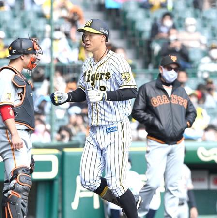 　拳を握りしめ生還する阪神・佐藤輝（右は巨人・原監督）