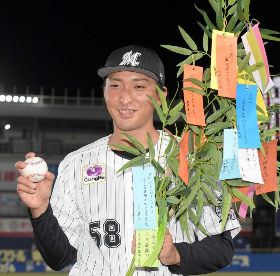 　プロ初勝利を挙げ、二木の応援コメントが書かれた短冊の七夕飾りを持って笑う河村（撮影・三好信也）