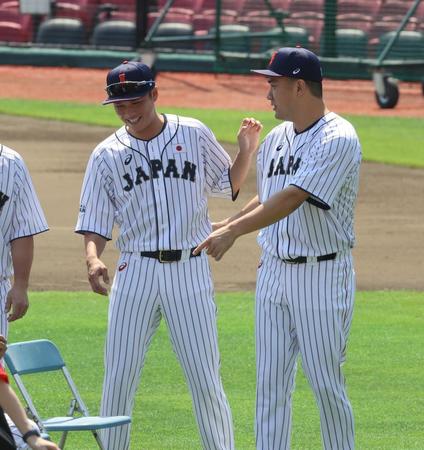 　集合写真の撮影で席を譲り合う田中将（右）と坂本　