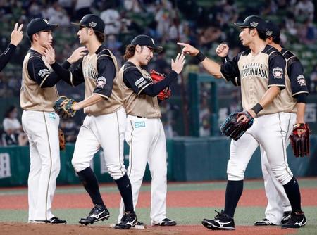 プロ初完投初完封で８勝目を挙げ、ナインとタッチを交わす日本ハム・伊藤（中央）＝メットライフドーム