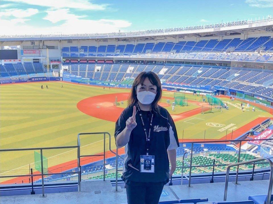 「１０００勝まで１勝」のポーズをしている場内アナウンス担当の谷保さん（球団提供）