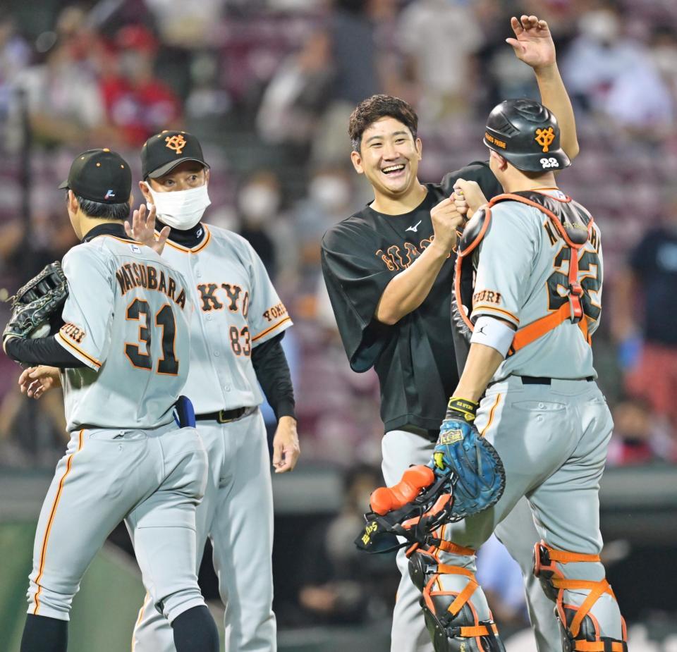 　チーム連敗を止める４勝目を挙げ、笑顔で小林（右）とタッチを交わす菅野。左隣は原監督