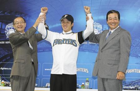 ユニホームに袖を通し、梨田監督（右）、藤井球団社長（左）と笑顔の斎藤佑＝２０１０年１２月９日、札幌ドーム