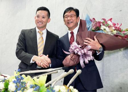 　退任の記者会見で選手から花束を贈られ、笑顔で握手を交わす栗山監督（右）