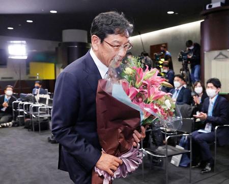 　退任の記者会見を終え、花束を手に引き揚げる栗山監督
