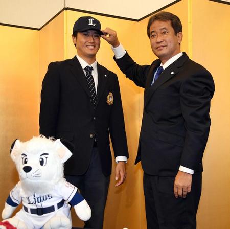 　グループディレクターに帽子をかぶせてもらう西武ドラフト２位の筑波大・佐藤（左）