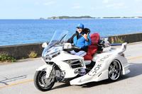 　沖縄の海を背に三輪バイクで走る新庄ビッグボス（撮影・高石航平）