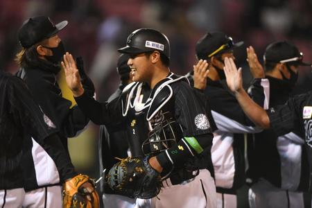 　開幕戦で楽天を破り今季初勝利を挙げた先発の石川（左後方）らナインとタッチを交わす松川（手前）＝撮影・開出牧