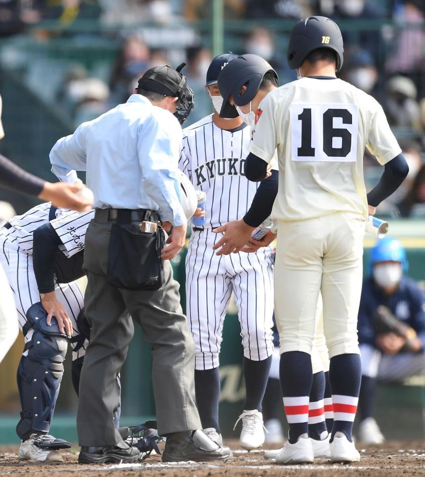 　７回、日高の打球が直撃した九州国際大付の捕手・野田（左）にコールドスプレーを差し出す浦和学院のランナーコーチ（撮影・伊藤笙子）