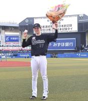 　完全試合達成を告げるスコアボードを背に花束とウイニングボールを手に笑顔の佐々木朗（撮影・開出牧）