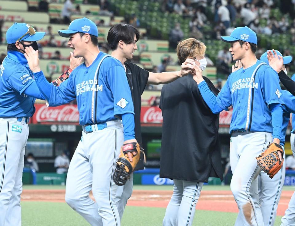 　試合に勝利し、今季初勝利のウイニングボールを石井から受け取る上沢（撮影・高石航平）