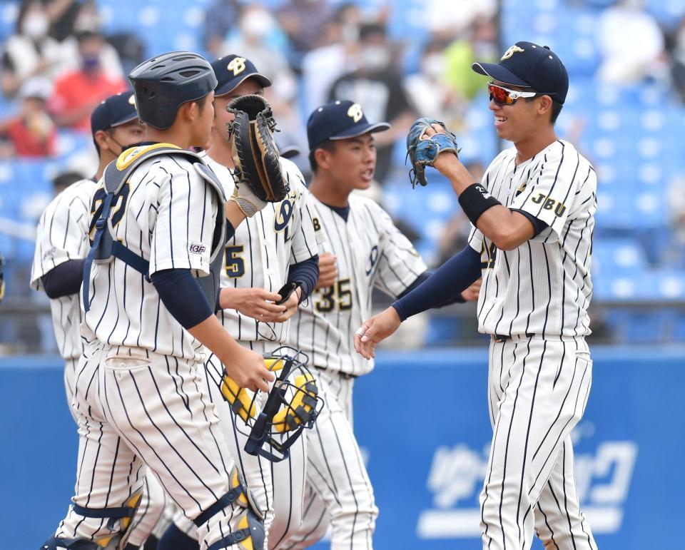 　仏教大に勝利し、ナインとタッチを交わす上武大・島村大樹（右）＝撮影・西岡正