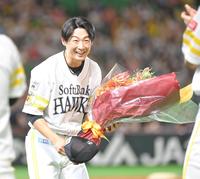 　通算１０００試合出場を達成し、花束を手に笑顔を見せる明石（撮影・高部洋祐）