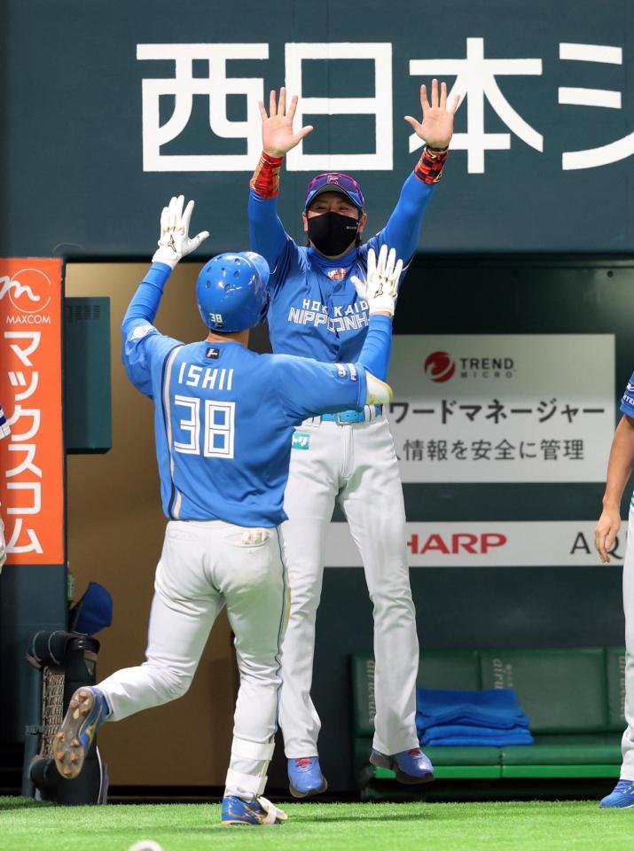 　延長１０回、２ランを放った石井（左）を笑顔で出迎える新庄監督