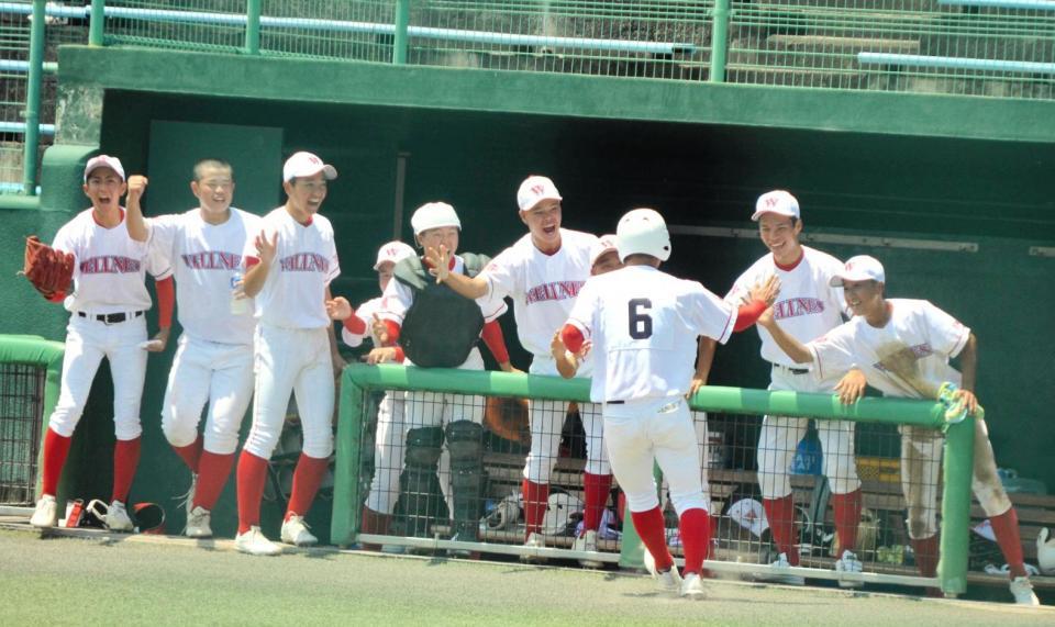 　３点目の本塁を踏んだ主将の長谷川を笑顔で迎える日本ウェルネスのナイン