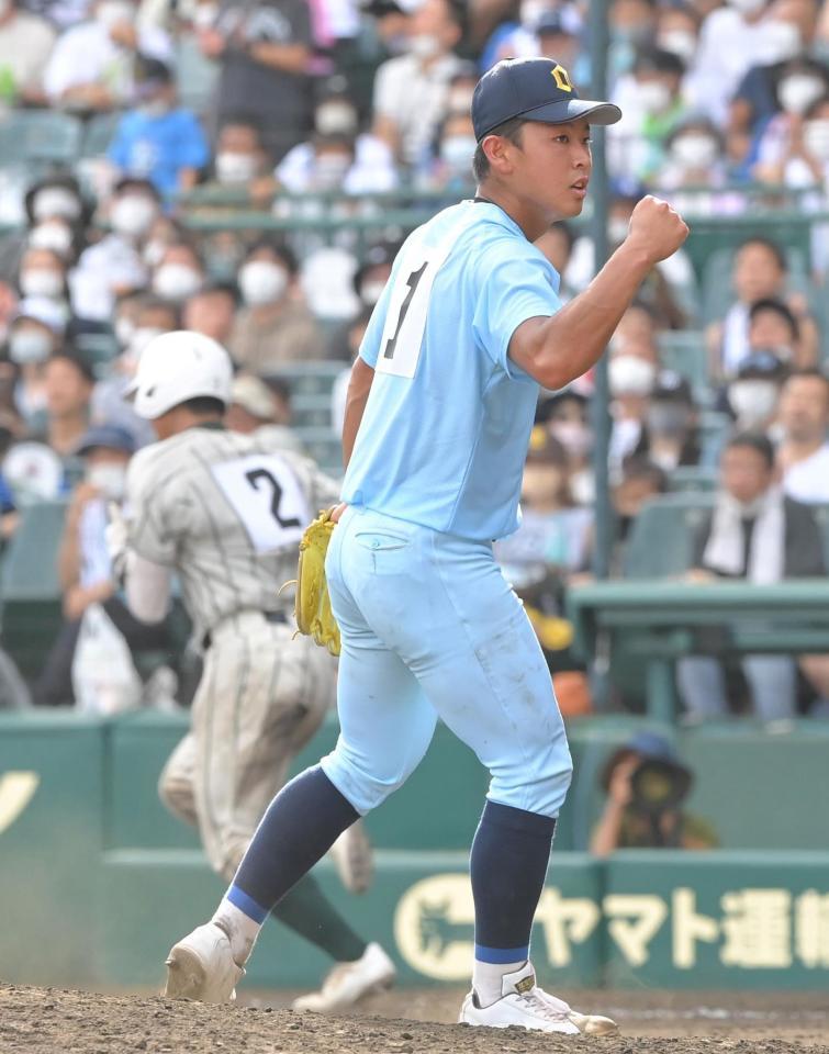 　７回、ピンチに鶴岡東・土屋奏人（左奥）を併殺に仕留め、ガッツポーズを決める近江・山田陽翔（撮影・高部洋祐）