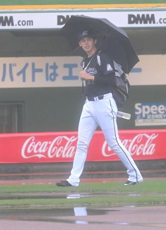 雨天中止が決定し、傘をさして引き揚げる佐々木朗（撮影・高部洋祐）