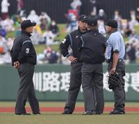 　８回が始まる前に試合続行について協議する審判員たち（撮影・中島達哉）